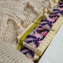 Lade das Bild in den Galerie-Viewer, Das Bild zeigt mehrere rechteckige Seifenstücke der Marke Fragantura, nebeneinander in einer weißen Holzkiste arrangiert. Die Seifen sind in florale Papierbanderolen mit der Aufschrift „Fragantura – Natürliche Duschseife – Blütengarten – Rosengeranie – Lavendel“ verpackt. Darüber liegen Sisalsäckchen mit Kordelzug und Holzperlen. Das Gesamtbild wirkt natürlich und ordentlich.