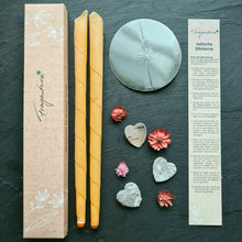 Lade das Bild in den Galerie-Viewer, Zwei orange Fragantura Ohrenkerzen mit Zubehör, Anleitung und kleinen Blumenherzen arrangiert.