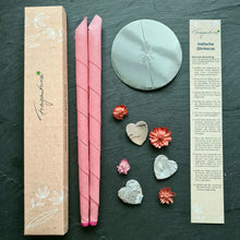 Lade das Bild in den Galerie-Viewer, Zwei rosa Fragantura Ohrenkerzen mit Metallteller, Anleitung und Deko auf dunklem Untergrund.