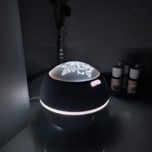 Lade das Bild in den Galerie-Viewer, Weißer Aromadiffusor mit floral gravierter Leuchtkuppel, eingeschaltet mit neutralweißem Licht im dunklen Raum