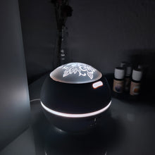 Lade das Bild in den Galerie-Viewer, Weißer Aromadiffusor mit floral gravierter Leuchtkuppel, eingeschaltet mit neutralweißem Licht im dunklen Raum