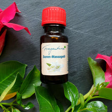 Lade das Bild in den Galerie-Viewer, Kleine braune Glasflasche mit rotem Deckel, etikettiert mit „Fragantura Damm-Massageöl“. Auf dem Etikett ist eine Lilie abgebildet. Die Flasche liegt auf grauem Untergrund, umrahmt von frischen roten Blumen mit grünen Blättern.
