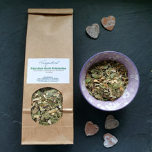 Lade das Bild in den Galerie-Viewer, Kraftpapierbeutel mit dem Etikett „Fühl dich leicht-Kräutertee“ von Fragantura neben einer lila Schale mit dem losen Kräutertee. Auf dem schwarzen Untergrund liegen dekorativ drei kleine Holzherzen.
