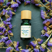 Lade das Bild in den Galerie-Viewer, Grüne Glasflasche mit Holzdeckel, etikettiert mit der Aufschrift "Fühl dich wohl – Massageöl für Mutti und Kind" der Marke Fragantura. Die Flasche ist von violetten Trockenblumen umrahmt und steht auf schwarzem Naturstein.