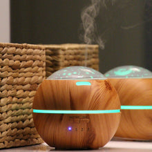 Lade das Bild in den Galerie-Viewer, Ein Aromadiffusoren in Holzoptik vor einem Spiegel mit Lichtprojektion (Sterne und Mond), auf hellem Untergrund