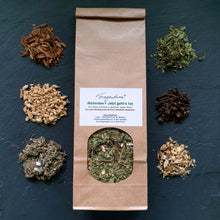 Lade das Bild in den Galerie-Viewer, Die geöffnete Papiertüte „Wehentee – Jetzt geht’s los“ steht mittig auf dunklem Untergrund. Um sie herum sind sechs kleine Portionen der enthaltenen Zutaten dekorativ drapiert: Zimtrinde, getrocknete Ingwerstücke, Eisenkraut, Beifuß, Liebstöckel und Nelken. Das Etikett auf der Tüte ist klar lesbar. Der Hintergrund ist neutral dunkelgrau gehalten und ohne weitere Deko.