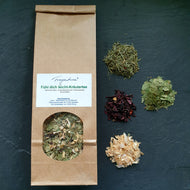 Packung „Fühl dich leicht-Kräutertee“ von Fragantura steht mittig. Rundherum angeordnet sind die einzelnen Zutaten als kleine Häufchen: Bohnenschalen, Schachtelhalm, Hibiskusblüten, Birkenblätter.